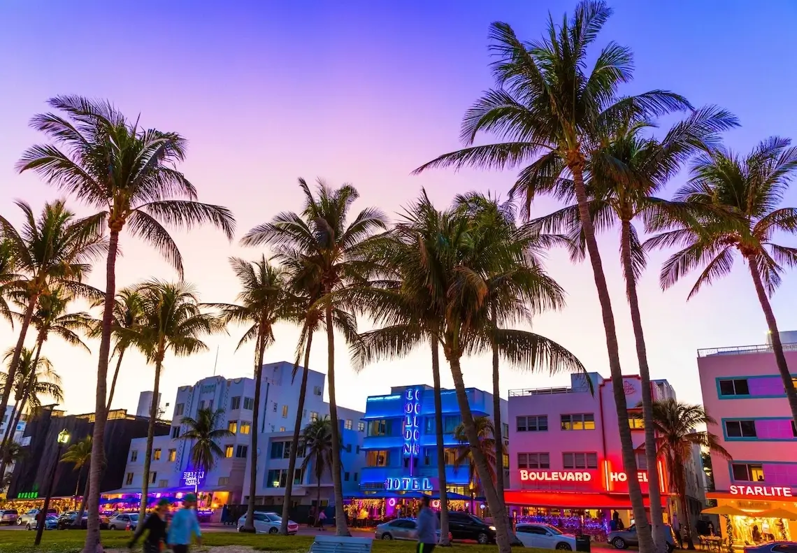 Пальмы и неоновые вывески отелей на Ocean Drive в Майами на закате